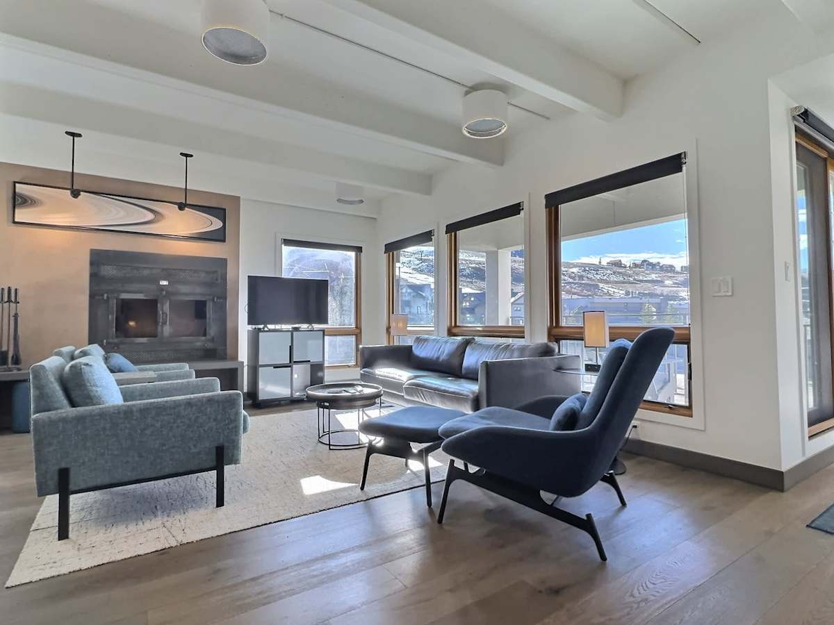 【Living Room】Wall of mountain windows and a sectional — where the crew lands when ski boots come off