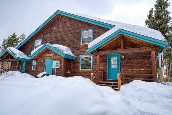【Exterior】The Giddy Betsy in summer — log siding, porch with BBQ, designated parking out front.
