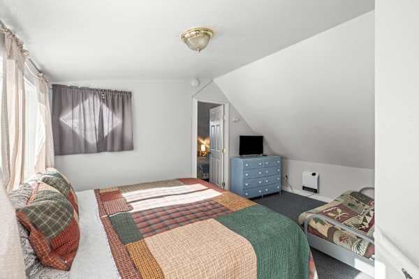 【Bedroom 1, Upstairs】 King bed + futon — private en-suite through that door, TV and dresser included.
